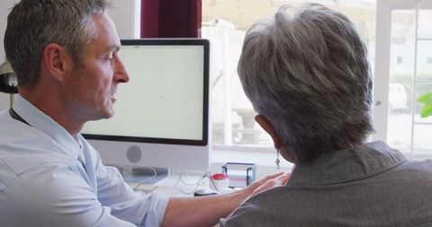 Doctor assisting senior woman with hearing aid in clinic setting