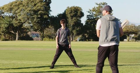 Outdoor cricket practice with diverse male friends training and playing on sunny field