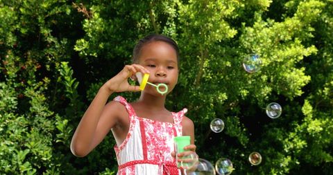 Young girl playing with bubbles in a park