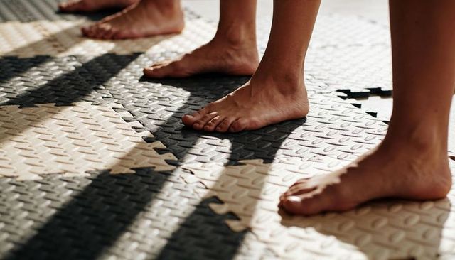 Group bare feet standing on interlocking foam mats casting long shadows