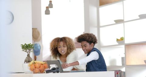 Mother Helping Son with Homework on Tablet in Modern Kitchen