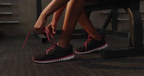 Active Woman Tying Pink Laces in Gym Setting