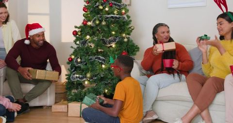 Family Exchanging Gifts Around Christmas Tree in Living Room