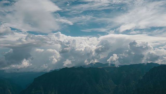 Billowing clouds towering over rugged alpine ridge with cirrus streaks