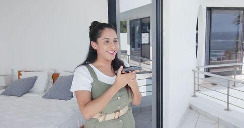 Woman Enjoying Voice Message in Modern Coastal Bedroom