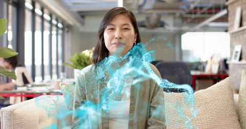 Korean woman sitting on sofa with blue hologram overlay in modern coworking space portrait