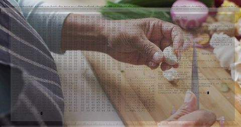 Senior indian hands peeling radish on wooden cutting board with digital code overlay