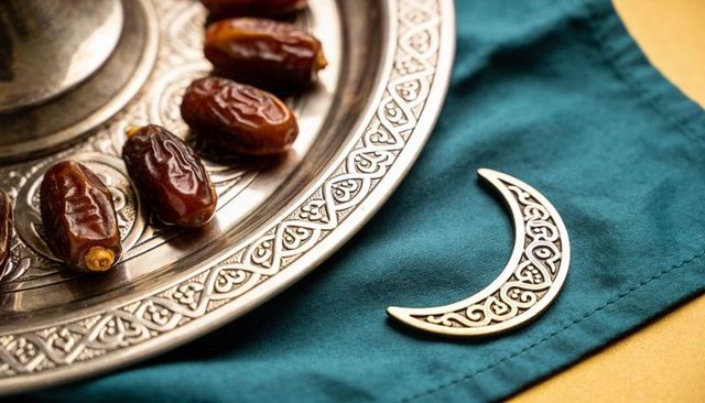 Closeup ramadan iftar dates on ornate silver tray with filigree crescent on teal fabric