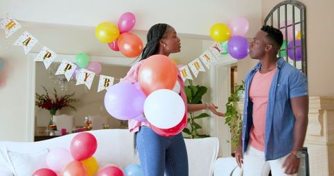 Happy couple preparing birthday party with colorful balloons