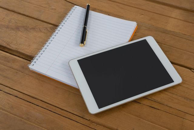 Close-up of blank notepad and digital tablet on wooden plank