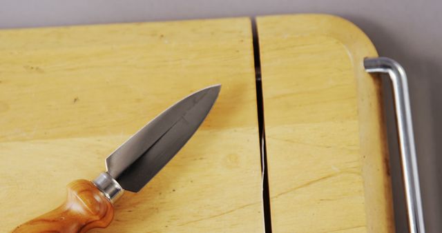 This stock photo shows a close-up view of a stainless steel chef knife placed on a wooden cutting board. The sharp, pointed blade and wooden handle highlight the quality and craftsmanship of the tool. This ideal for use in culinary blogs, cooking websites, kitchen equipment stores, or food preparation tutorials.