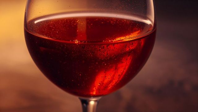 Elegant red sparkling drink in stemmed glass on dimly lit evening