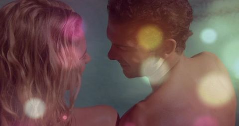 Romantic couple gazing over bare shoulders with soft bokeh teal backdrop