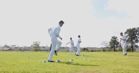 Male Teammates Performing Drills on Field with Blue Cones