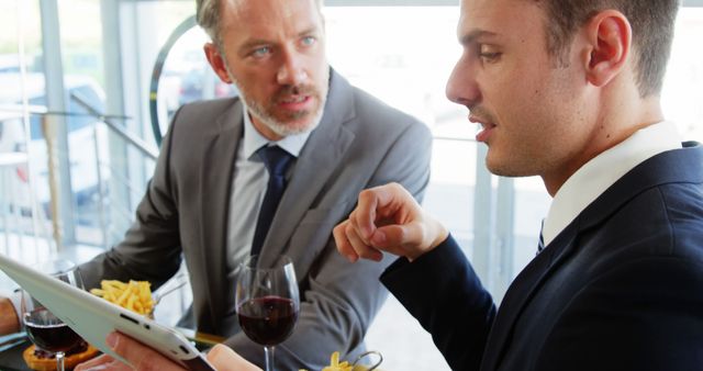 Two men watching a tablet at restaurant 