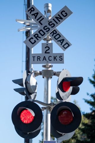 Railroad crossing with red signal lights on clear day