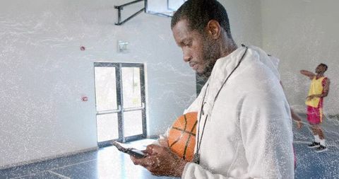 Coach with Phone and Basketball Consulting Sports Strategy in Gym