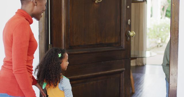 Image of happy african american mother and daughter trick or treating at grandmother's house. Family, domestic life and togetherness concept digitally generated image.