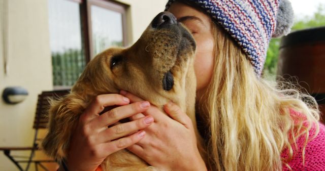 This heartwarming and cozy image of a young woman embracing her golden retriever is perfect for highlighting the bond between humans and their pets. Ideal for use in pet care campaigns, advertisements for pet products, social media content focused on companionship, and articles about the emotional benefits of having pets.