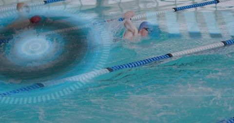 Swimmers competing in indoor pool wearing caps and goggles