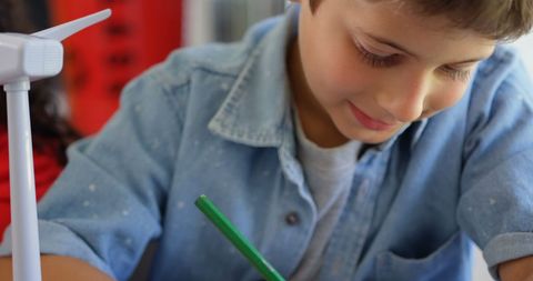 Young boy learning in classroom, smiling and studying heredly