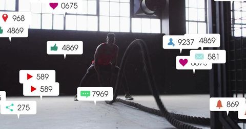 Male athlete training with battle ropes in industrial warehouse gym silhouette, hiit focus