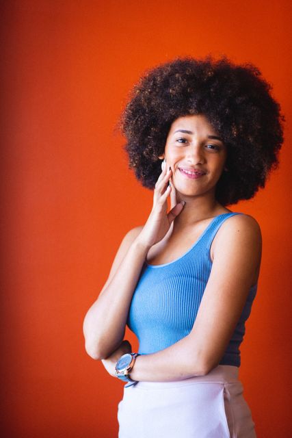 Portrait of afro young african american businesswoman smiling against orange wall, copy space. unaltered, business, corporate business, occupation and office concept.