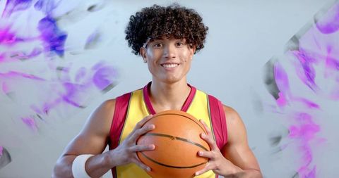 Smiling Athlete Holding Basketball against Vibrant Backdrop
