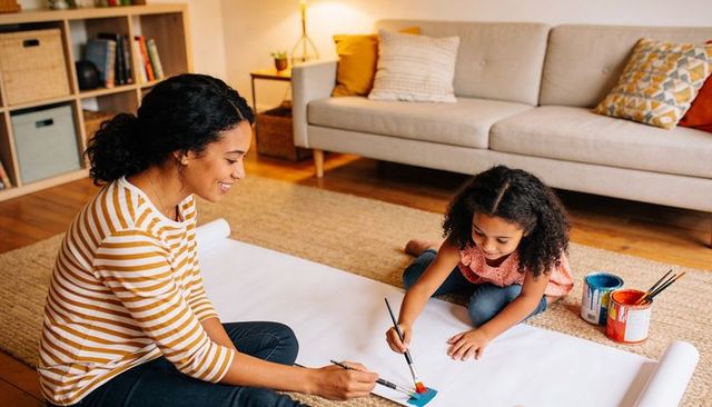 Mother and daughter painting together on living room floor creating colorful family art