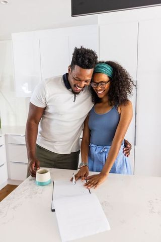 African american couple signing home documents at bright modern kitchen island