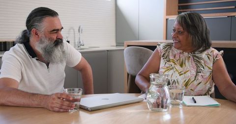 Senior Couple Enjoying Time at Home with Laptop and Drinks