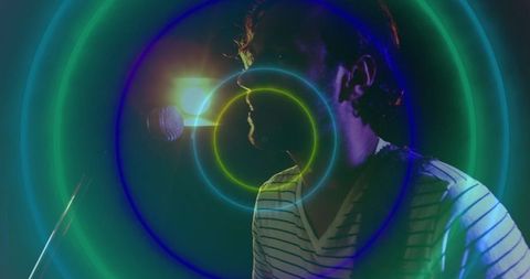 Musician performing on stage with neon light rings