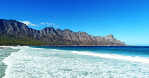 transparent waters meeting rugged mountain coastline under blue sky - Download Free Stock Videos Pikwizard.com