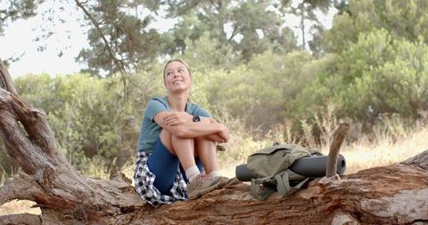 Thoughtful Young Woman Resting on Fallen Tree During Outdoor Adventure - Download Free Stock Images Pikwizard.com