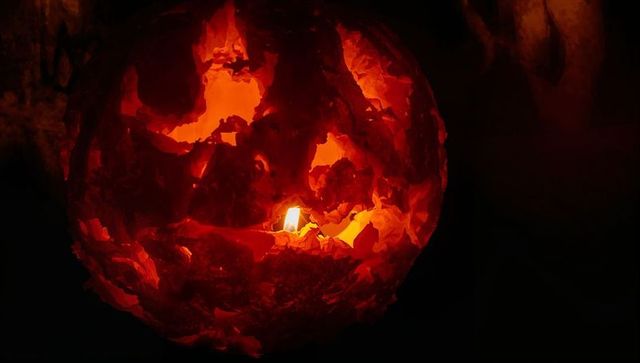 Eerie jack-o'-lantern with flickering flame in dark room