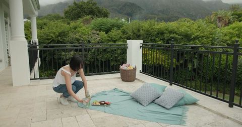 Woman Setting up Picnic on Scenic Terrace with Mountain View