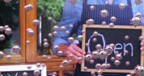 Small Business Owner with Open Sign Amidst Virus Particles Highlighting Pandemic Challenges