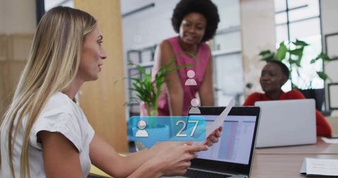 Reviewing documents over laptop during collaborative office meeting showing analytics alert