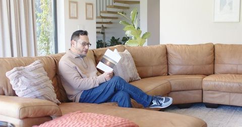 Man Reading Book on Tan Leather Sectional Sofa in Cozy Living Room