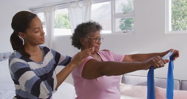 Young Therapist Assisting Elderly Woman with Exercise Band at Home - Download Free Stock Images Pikwizard.com