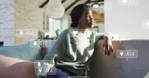 Pensive woman lounging on sofa with social media notification overlays in bright living room