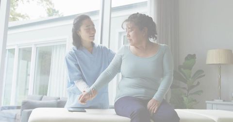 Caregiver guiding senior woman through gentle arm rehabilitation at home