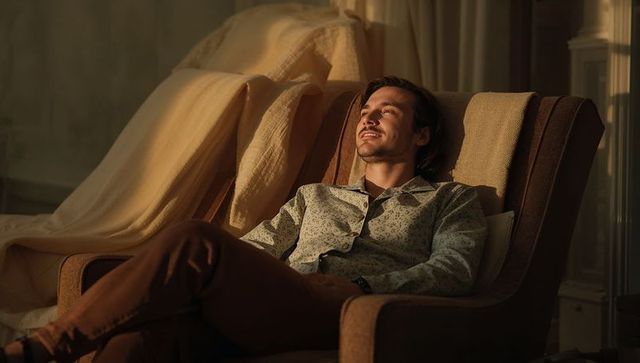 Golden hour relaxation: man reclining in armchair, warm sunlight flooding cozy interior