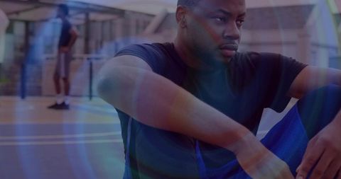 Pensive athlete resting on urban basketball court