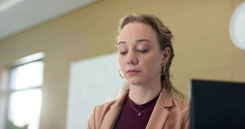 Young professional woman working on laptop in modern office classroom with focused expression