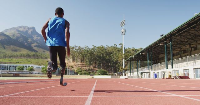African american male athlete prosthetic legs training at empty stadium, copy space. Sport, disability, atletics and fitness, unaltered.