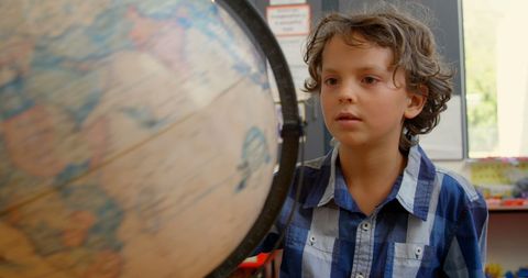 Inquisitive Schoolboy Examining Rotating Globe in Classroom Setting - Download Free Stock Images Pikwizard.com