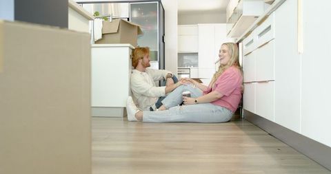 Happy Couple Enjoying Coffee and Chatting Amidst Kitchen Moving Boxes