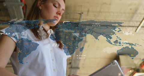 Female professional holding tablet viewing ar world map overlay in industrial workspace