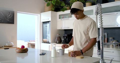 Adult african man preparing morning drink in modern minimalist kitchen with island